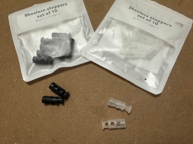 白っぽい半透明とブラックの、靴ひもストッパー10個セットのふくろとストッパーがふたつずつうつった写真。ジッパーつきのふくろにストッパーが10こずつハイっています