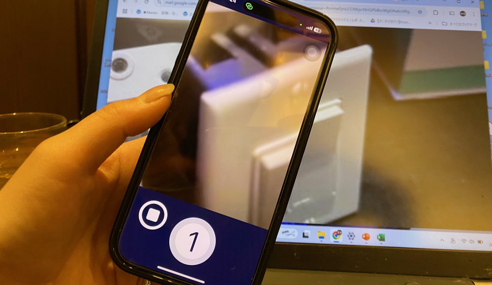 パソコンのモニターに説明が難しいと感じたアメリカの家電のスイッチを拡大表示し、そのよこに手に持ったスマホがうつった写真。スマホの画面はアプリのエンヴィが起動されています