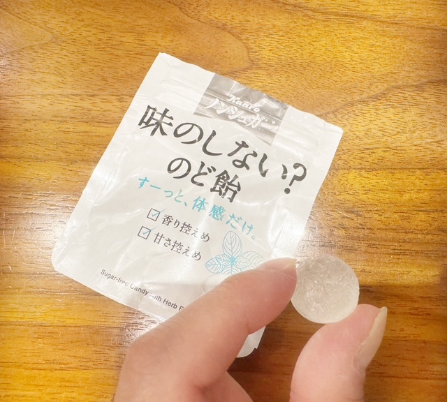 あじのしないのど飴をひとつぶてでつまんだ手元の写真。ひとくちサイズで白っぽい飴です