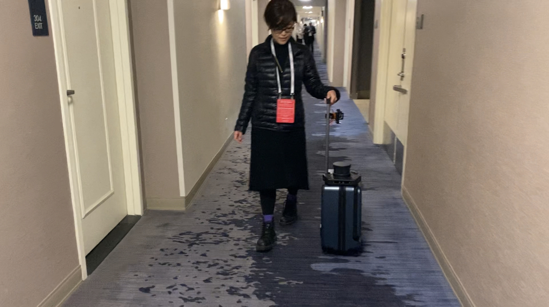 アメリカでおこなわれたシーサンで公開された屋内用エーアイスーツケースに誘導してもらい、ホテルのロビーを歩く女性の写真